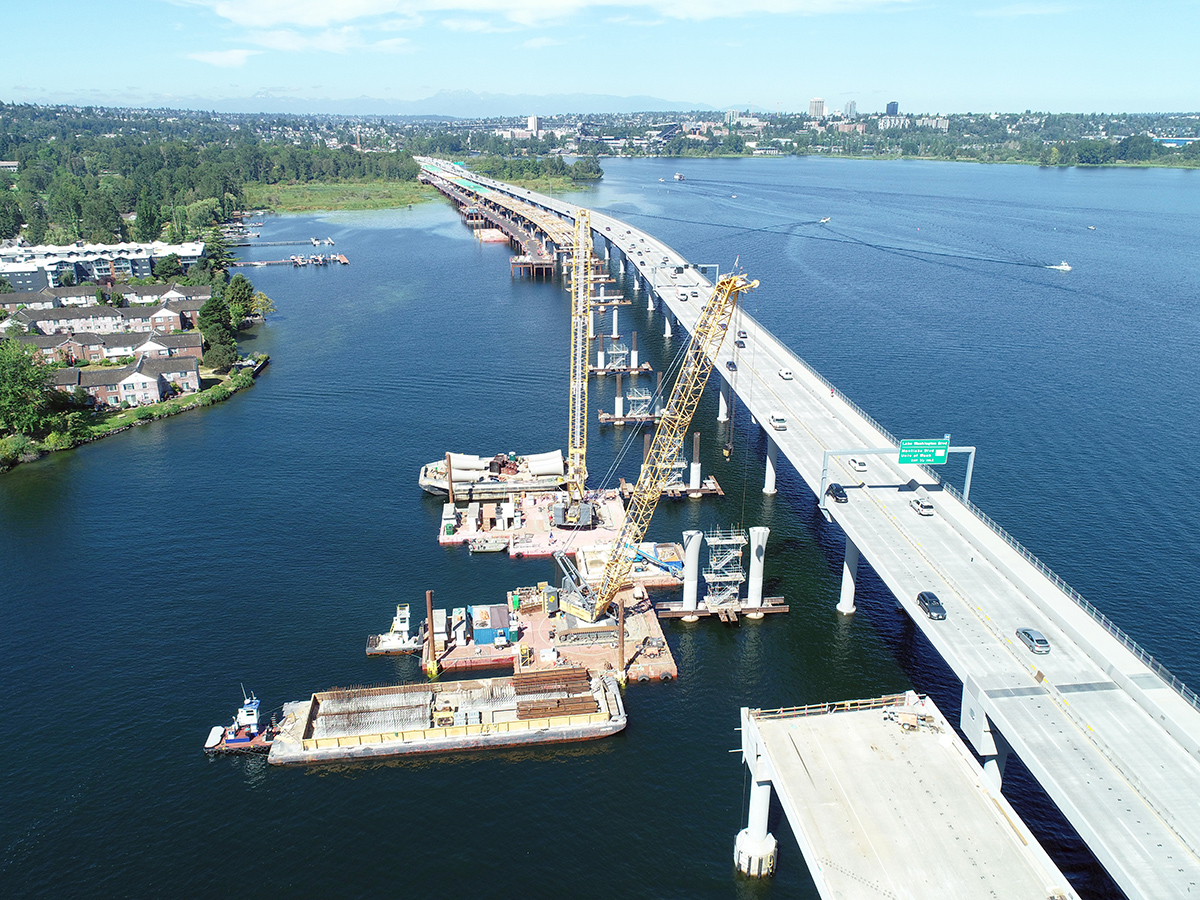 Cranes on barges are staged near the SR 520 floating bridge during construction.