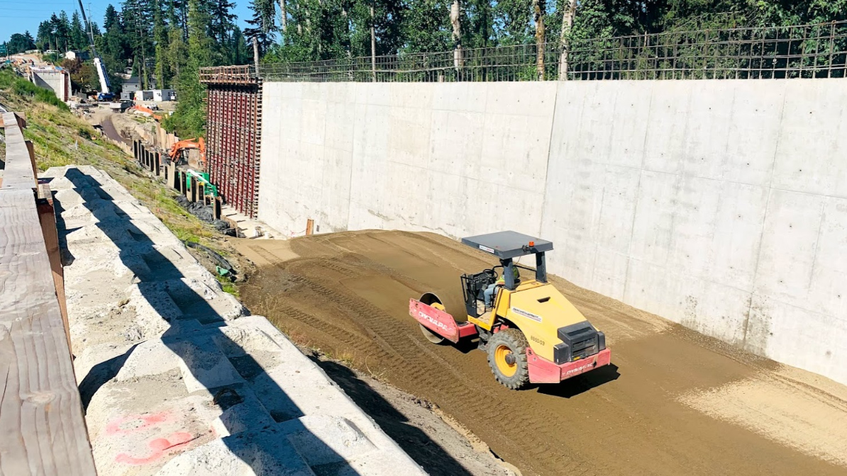 A vibratory roller is shown rolling up and down a section of soil to help make it compact for construction.