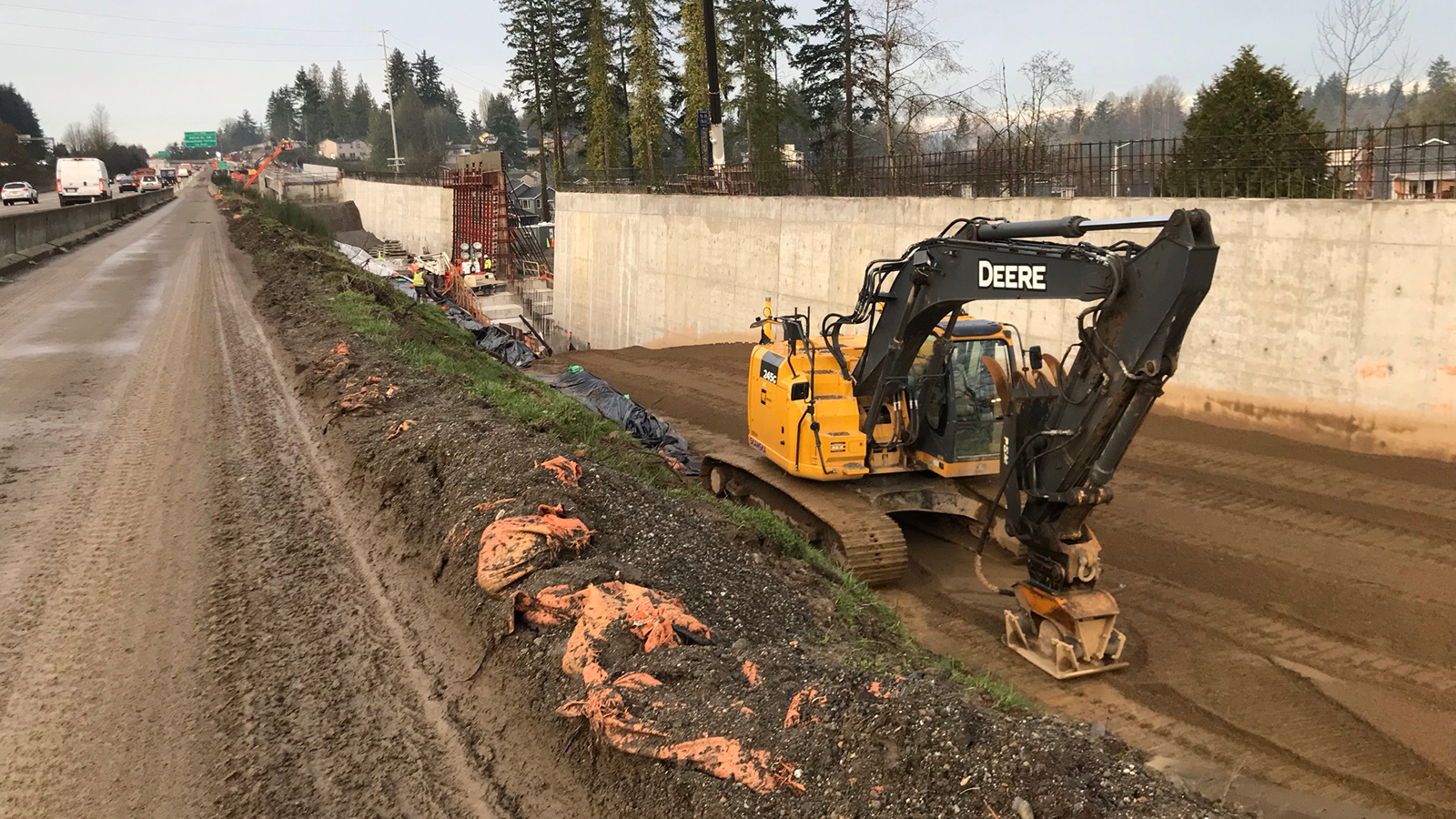 An excavator has an attachment on its arm to hammer the ground which helps compact soils.