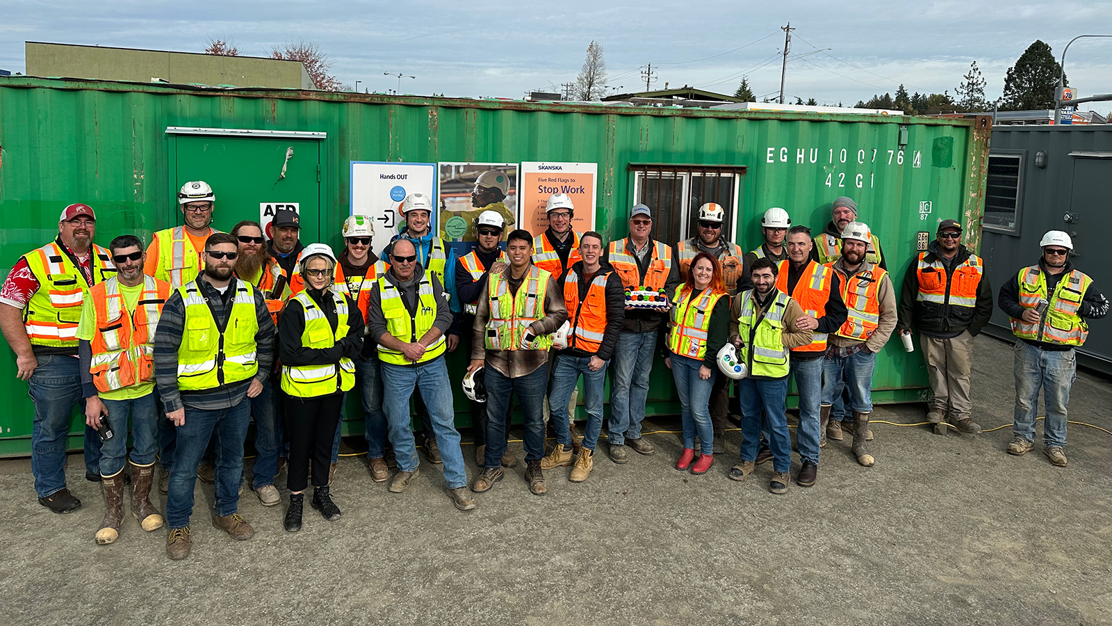 A group of people wearing Skanska-branded construction gear pose for a photo at a SR 520 construction site.