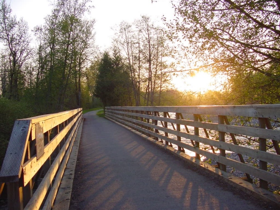 Foto del puente peatonal y para bicicletas del sendero Foothills sobre un río al atardecer