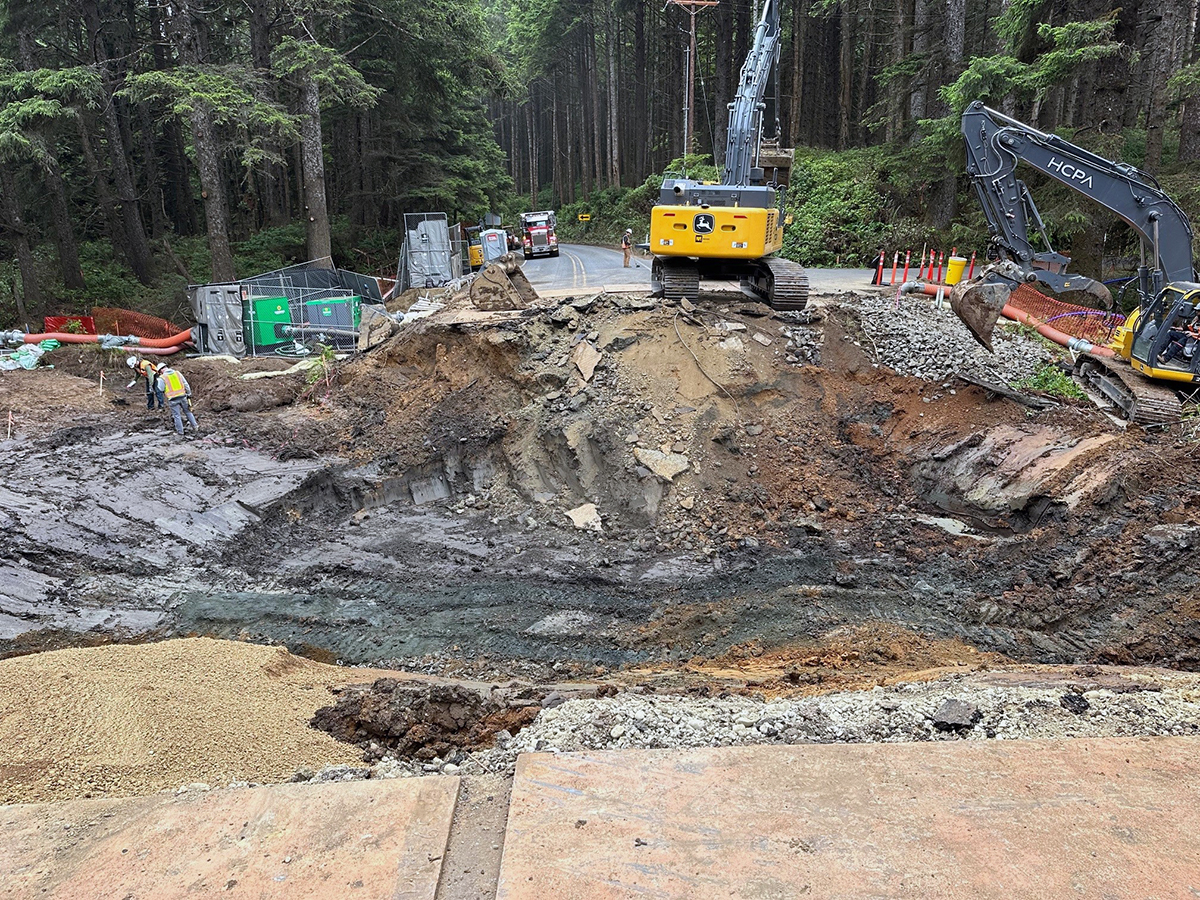 Image of a roadway completely dug up for construction. The ground is torn up and heavy equipment is visible.