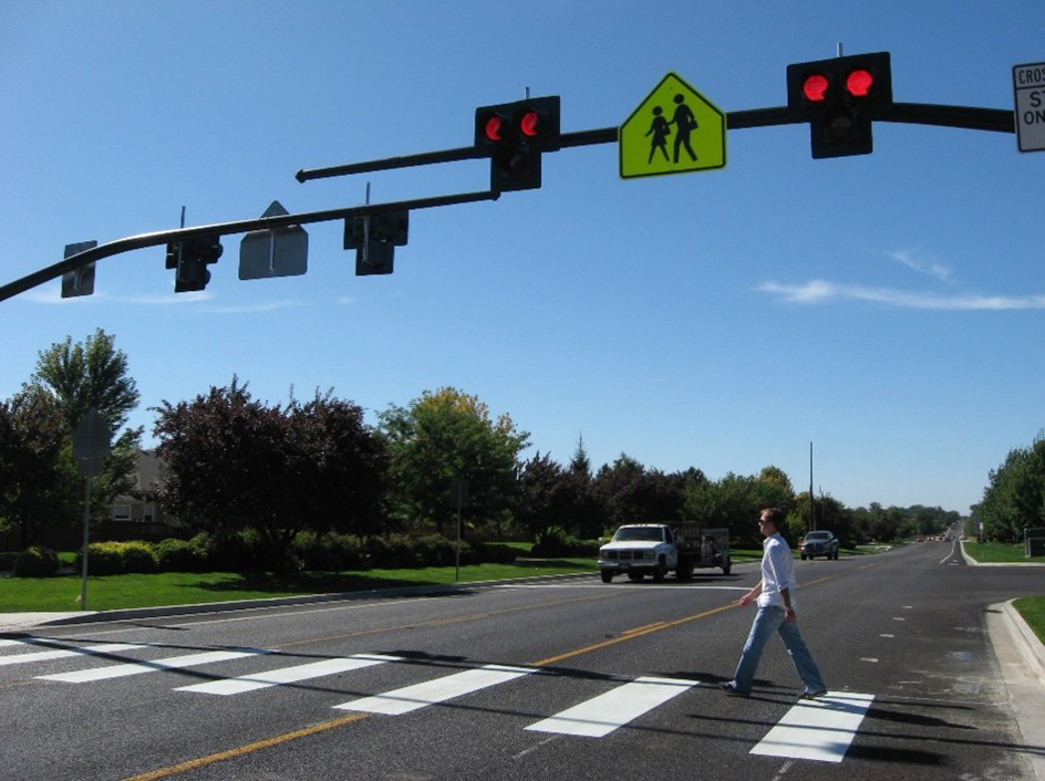 An image showing a crosswalk with a Pedestrian Hybrid Beacon, allowing all pedestrians to cross while vehicles are stopped at the red light.